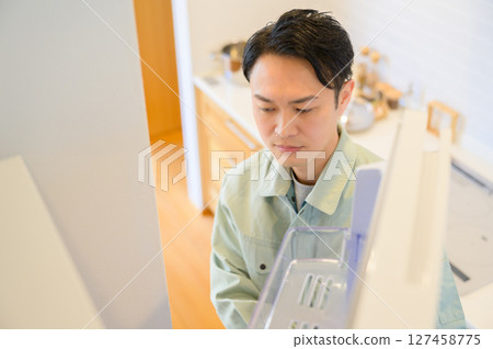 身穿工作服的日本男子檢查冰箱 身穿工作服的日本男子檢查冰箱 127458775