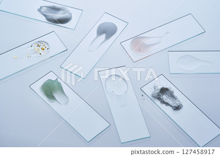 Various cosmetic products on slides on a dark gray background. 127458917