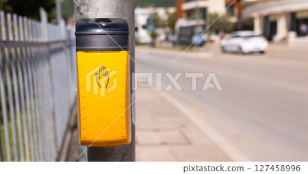 Pedestrian crossing button on sunny urban street. Urban navigation, road safety, and city transportation infrastructure. Copy space 127458996