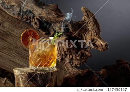 An old-fashioned cocktail over ice on an old wooden stump. An old-fashioned cocktail over ice on an old wooden stump. 127459137