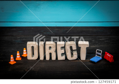 Concrete Word Direct with Traffic Cones and Mini Cart on Dark Wooden Surface 127459171