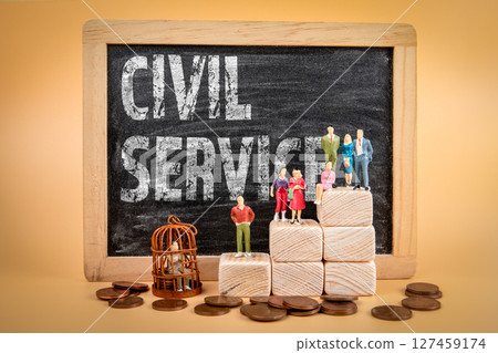Civil Service Concept with Miniature People, Chalkboard Text, and Coins on Wooden Background Civil Service Concept with Miniature People, Chalkboard Text, and Coins on Wooden Background 127459174