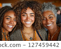 Three smiling women with curly hair showcasing joy and connection in a vibrant setting 127459442