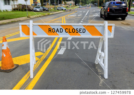 Road closure sign indicating detour with police vehicle in background on busy street during daytime 127459978