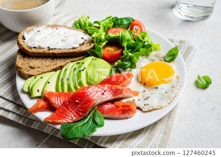 Healthy breakfast - fried egg, salmon, avocado and green salad 127460245