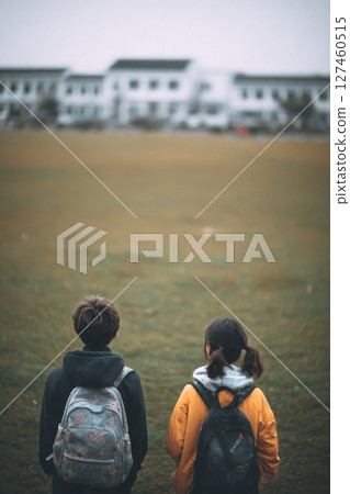 Children on a Grassy Field Facing Historic Buildings During a Cloudy Afternoon. 127460515
