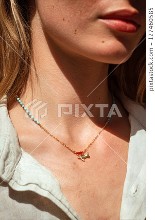 Beautiful Gold and Turquoise Necklace Adorned With a Fish Pendant Against a Neutral Background. 127460585