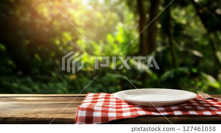 Picnic Setting With a Checkered Cloth and Empty Plate in a Lush Garden During Golden Hour. 127461038