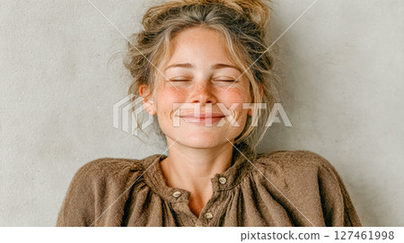 Smiling woman with natural beauty, wearing cozy sweater against neutral textured background 127461998