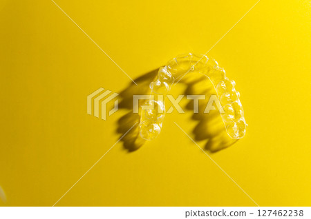 Invisible orthodontic cosmetic aligners on a gradient color background, teeth aligners, plastic braces. The way to have a beautiful smile and white teeth. Invisible orthodontic cosmetic aligners on a gradient color background, teeth aligners, plastic braces. The way to have a beautiful smile and white teeth. 127462238