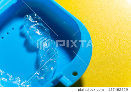 Close-up Blue plastic case with transparent brackets on a peach background. Invisible removable retainers for orthodontic treatment Close-up Blue plastic case with transparent brackets on a peach background. Invisible removable retainers for orthodontic treatment 127462239