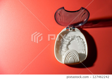 Transparent dental aligners lie in a case on a colored background. Aesthetic and comfortable correction of jaw bite. Copy space Transparent dental aligners lie in a case on a colored background. Aesthetic and comfortable correction of jaw bite. Copy space 127462242
