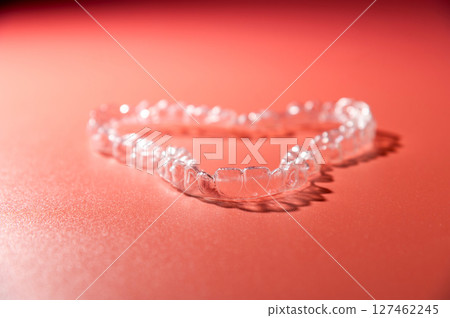 Invisible orthodontic cosmetic aligners on a gradient color background, teeth aligners, plastic braces. The way to have a beautiful smile and white teeth. 127462245