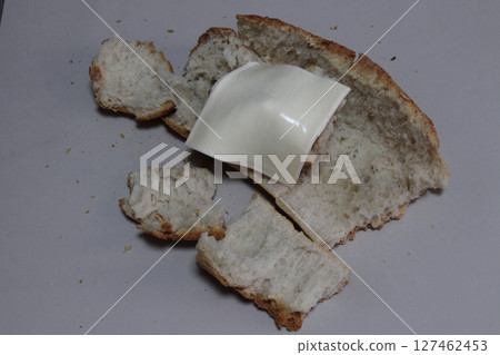 A broken baked baguette with melted cheese. A broken baked baguette with melted cheese. 127462453