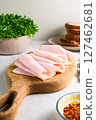 Close-up of sliced turkey ham arranged in elegant folds on a wooden cutting board. Fresh sandwich ingredients in the background 127462681