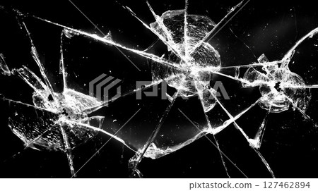 Shattered glass pattern revealing fragmented surface with radiating cracks across dark backdrop 127462894