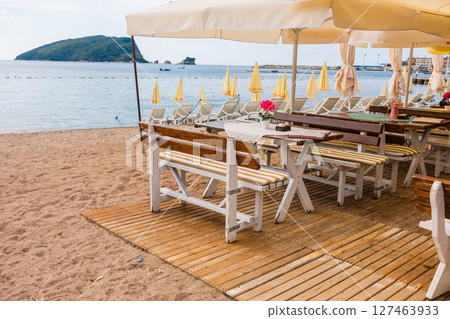 Outdoor cafe or restaurant with sea view and empty chairs. Coastal relaxation, summer tourism, and beachfront dining in the Mediterranean region. 127463933