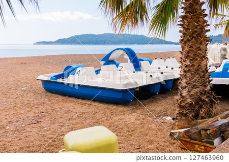 Blue and white pedal boats on shore. Summer recreation, water sports, and tourism infrastructure close-up 127463960
