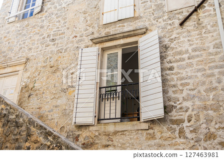 Rustic window with open wooden shutters. Mediterranean charm, urban gardening and cozy architecture. Rustic window with open wooden shutters. Mediterranean charm, urban gardening and cozy architecture. 127463981