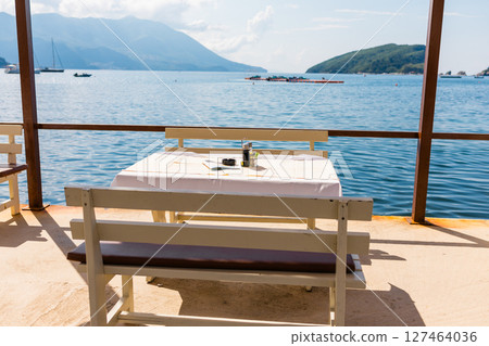 Outdoor cafe or restaurant with sea view and empty chairs. Coastal relaxation, summer tourism, and beachfront dining in the Mediterranean region. Outdoor cafe or restaurant with sea view and empty chairs. Coastal relaxation, summer tourism, and beachfront dining in the Mediterranean region. 127464036