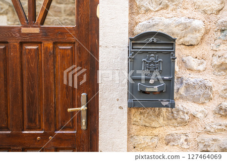 Antique wall-mounted mailbox with decorative coat of arms. Summer travel, vintage communication, and historic European street culture. Copy space 127464069
