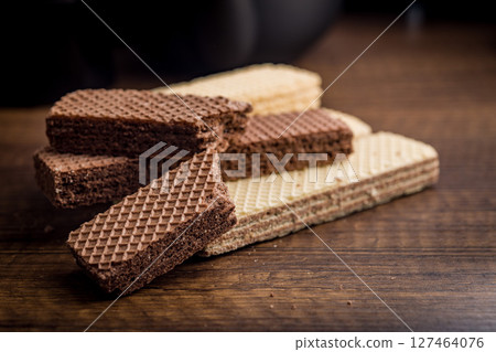 Sweet wafers filled with chocolate and vanilla cream on wooden table. 127464076