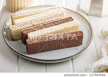 Sweet wafers filled with chocolate and vanilla cream on plate on white table. 127464080