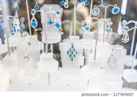 Display of handmade silver pendants with blue stones. Jewelry, elegance, and artisan craftsmanship highlighted in a boutique window. Display of handmade silver pendants with blue stones. Jewelry, elegance, and artisan craftsmanship highlighted in a boutique window. 127464087