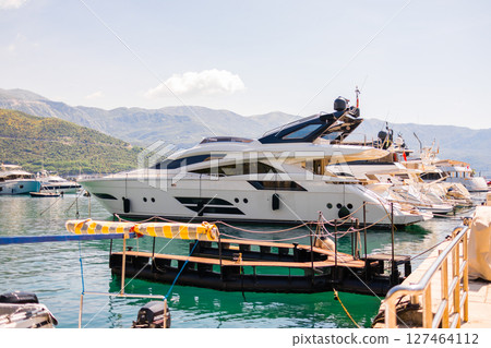 Luxury yacht docked in scenic marina on a sunny coastal day. Summer travel, elite leisure, and the lifestyle of Mediterranean seaside tourism. Luxury yacht docked in scenic marina on a sunny coastal day. Summer travel, elite leisure, and the lifestyle of Mediterranean seaside tourism. 127464112