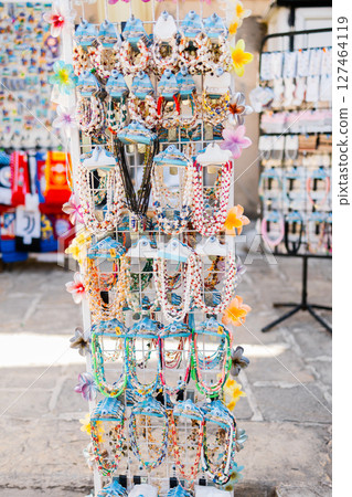 Colorful bead necklaces on tourist souvenir display. Summer travel, local craftsmanship, and coastal marketplace culture in Mediterranean street shops. 127464119