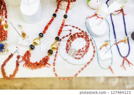 Red coral necklaces displayed on white showcase. Traditional jewelry, handcrafted coastal accessories, and natural gemstone aesthetics highlight regional artisanal heritage. 127464123