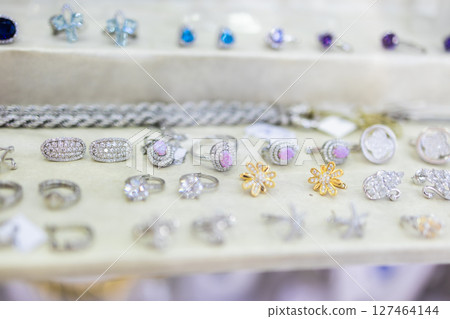 Jewelry assortment in luxury boutique window. Silver accessories, gemstone details, and elegant craftsmanship for fashion-forward retail styling. Jewelry assortment in luxury boutique window. Silver accessories, gemstone details, and elegant craftsmanship for fashion-forward retail styling. 127464144