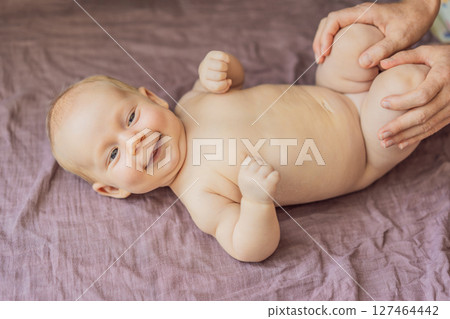Newborn baby lying on a soft blanket while mother gently exercises the babys tiny limbs. Early development, bonding, and baby care concept Newborn baby lying on a soft blanket while mother gently exercises the babys tiny limbs. Early development, bonding, and baby care concept 127464442