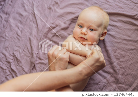 Newborn baby lying on a soft blanket while mother gently exercises the babys tiny limbs. Early development, bonding, and baby care concept Newborn baby lying on a soft blanket while mother gently exercises the babys tiny limbs. Early development, bonding, and baby care concept 127464443