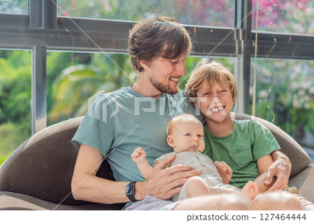 Father, son, and newborn baby sitting on the couch, joyfully celebrating the newest addition to their family. Parenthood, bonding, and family love concept Father, son, and newborn baby sitting on the couch, joyfully celebrating the newest addition to their family. Parenthood, bonding, and family love concept 127464444