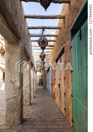 Old town in Al Seef Cultural Historical District on shores of Dubai Creek. Tourist place with old streets, houses and shops, Dubai, UAE. Vertical photo 127464465