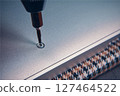 A close-up view of a screwdriver inserting a screw into a metallic surface, showcasing precision work. 127464522