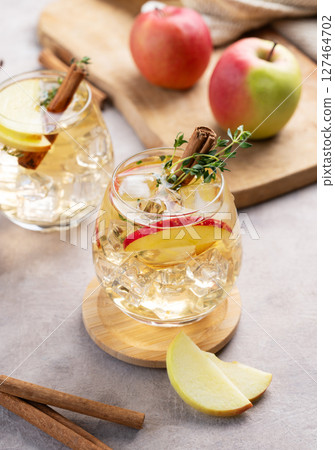 Apple cocktail or cider with cinnamon stick and thyme garnish on light background Apple cocktail or cider with cinnamon stick and thyme garnish on light background 127464702
