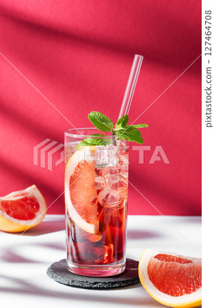 Refreshing cocktail with grapefruit, mint and ice in a glass on a white red background with shadow 127464708