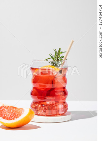 Refreshing mocktail with grapefruit, rosemary and ice in a glass on a light background with shadows. 127464714