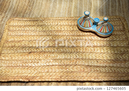 Decorative Tajine from Marrakech displayed on a table with an esparto grass rug Decorative Tajine from Marrakech displayed on a table with an esparto grass rug 127465605