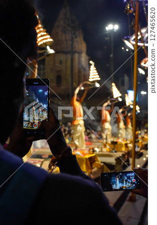 View of hands with phone taking photos at Aarti ceremony on bank of Ganges river View of hands with phone taking photos at Aarti ceremony on bank of Ganges river 127465620