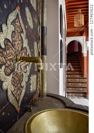 Faucet and fountain with Arabic stairs in background. Typical Marrakech courtyard 127465622