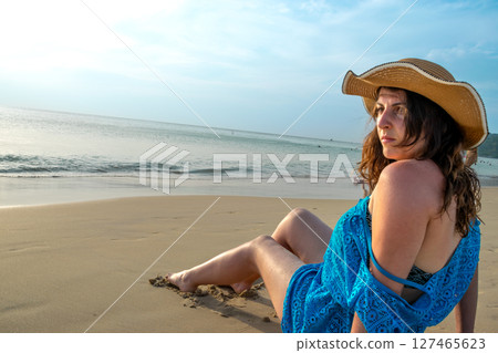 Rear view of young model observing horizon with hat on beach at Patong beach 127465623