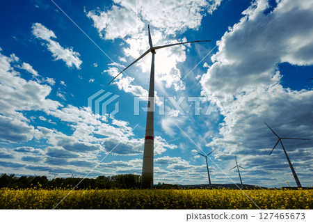 A field of wind turbines generating energy standing in a green field. 127465673