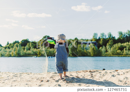 Happy 2 year old little boy playing on sand during summer vacation, wearing hat. Family travel and vacation, outdoor activities on summer beach holiday with children. 127465731