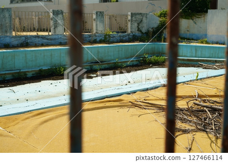 Abandoned swimming pool seen through rusty iron bars Abandoned swimming pool seen through rusty iron bars 127466114
