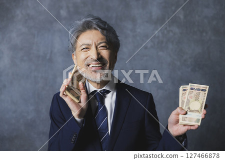 Smiling senior businessman holding a stack of bills 127466878
