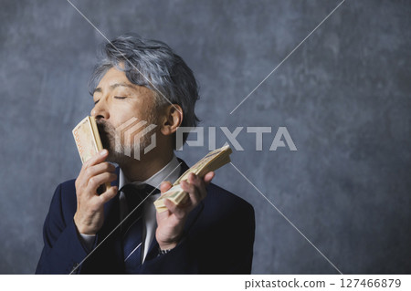 微笑的高級商人拿著一疊鈔票 127466879