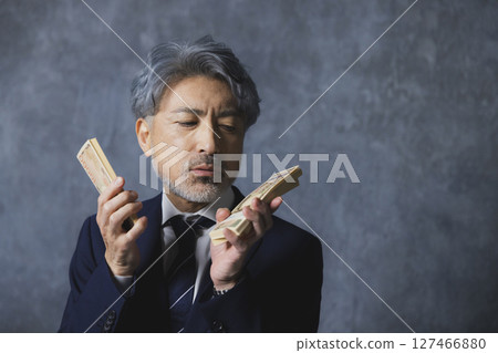 Smiling senior businessman holding a stack of bills 127466880